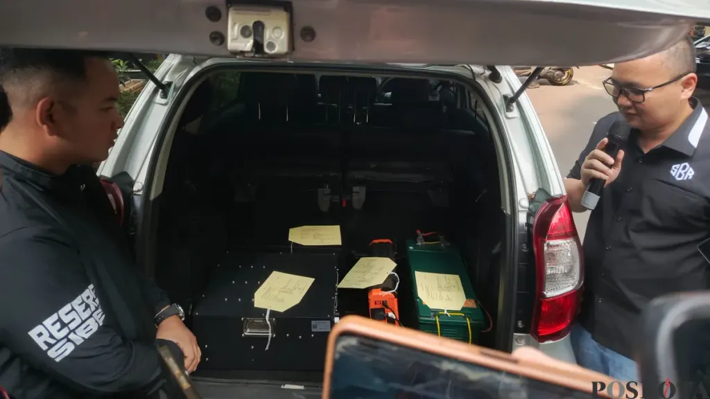 SMS blaster equipment displayed in the open boot of the silver car